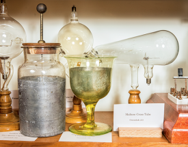 A collection of antique physics apparatus teaching devices on a shelf.