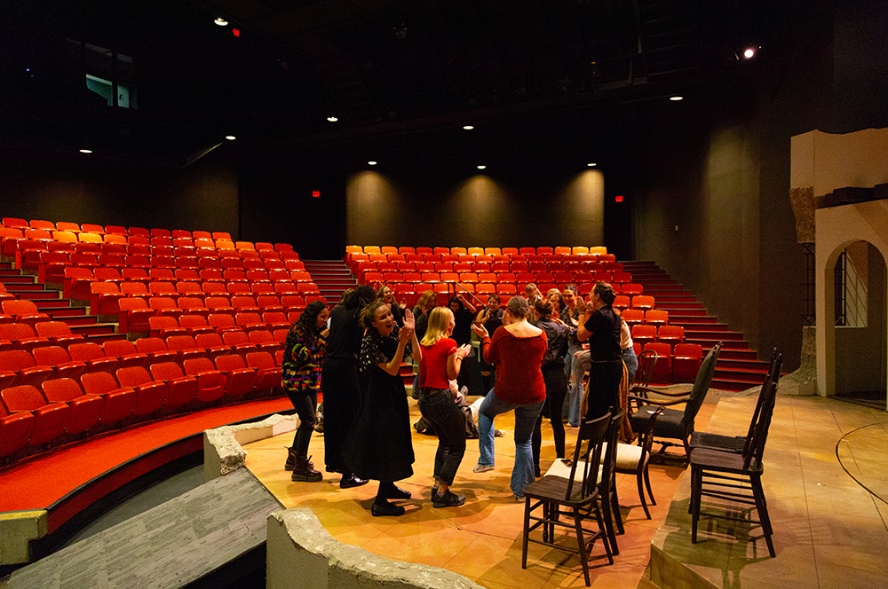 Actors dancing in a circle on stage